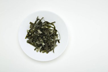 Beyaz bir tablo üzerinde beyaz bir tabak içinde kurutulmuş yosun mühür. Tasarım alanı olan doğal ışık ışık öykünür.