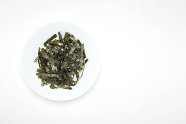 Beyaz bir tablo üzerinde beyaz bir tabak içinde kurutulmuş yosun mühür. Tasarım alanı olan doğal ışık ışık öykünür.