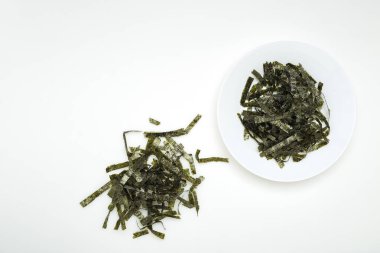 Beyaz bir tablo üzerinde beyaz bir tabak içinde kurutulmuş yosun mühür. Tasarım alanı olan doğal ışık ışık öykünür.