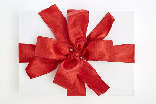 single white textured gift box with red ribbon bow on white background