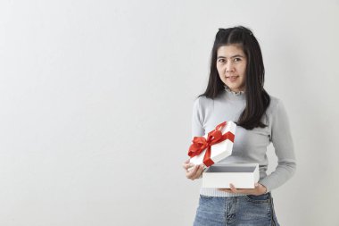 Genç Asyalı kadın gösterisi ile parlak gri duvar arka plan üzerinde bir hediye kutusu