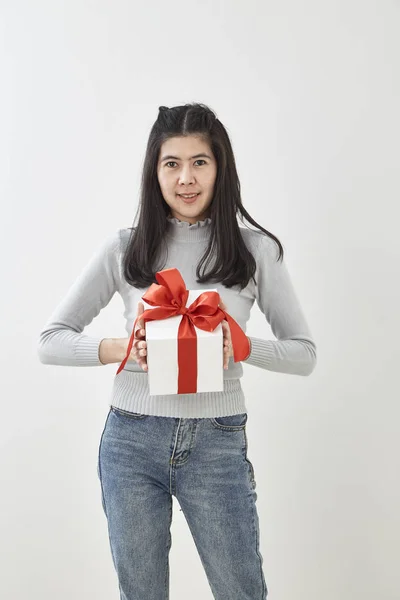 stock image Young Asian woman show  with a gift box on bright gray wall background