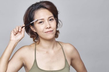 Gri arka plan, güzel moda kavramı üzerinde Kaş Fırçası aracıyla closeup güzel kadın
