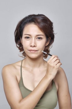 Gri arka plan, güzel moda kavramı üzerinde Kaş Fırçası aracıyla closeup güzel kadın