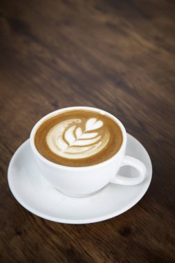 Sıcak latte kahve sıcak sabah güneş ışığı ile ahşap masa arka plan üzerinde. mutlu hafta sonu kavramı.