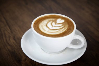 Sıcak latte kahve sıcak sabah güneş ışığı ile ahşap masa arka plan üzerinde. mutlu hafta sonu kavramı.