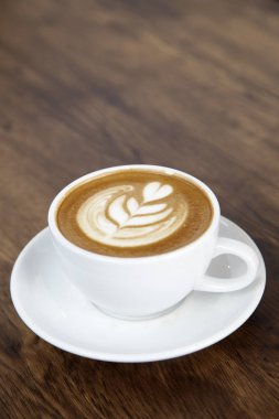 Sıcak latte kahve sıcak sabah güneş ışığı ile ahşap masa arka plan üzerinde. mutlu hafta sonu kavramı.