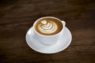 Sıcak latte kahve sıcak sabah güneş ışığı ile ahşap masa arka plan üzerinde. mutlu hafta sonu kavramı.