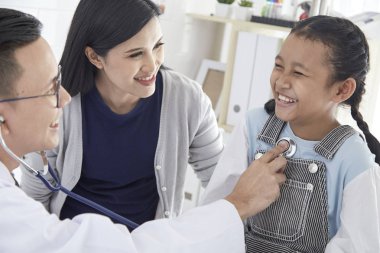 Doktor steteskoptaki hasta bir çocuğun akciğerlerini dinliyor. Annesiyle birlikte doktora geldi. Kız soğuk algınlığından hasta. Doktorun ışık odasındalar..