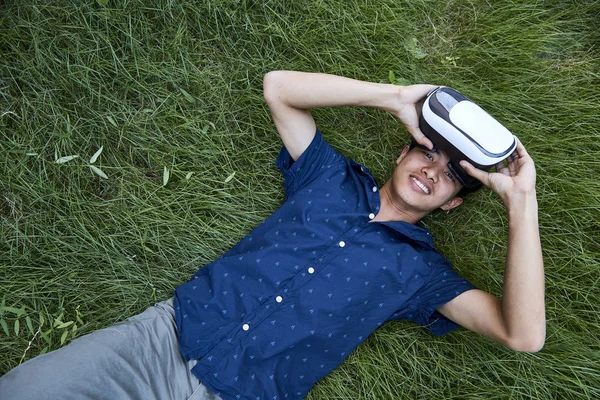 Азиатский Мужчина Наслаждается Виртуальной Реальностью Сидя Траве Открытом Парке Устройство — стоковое фото