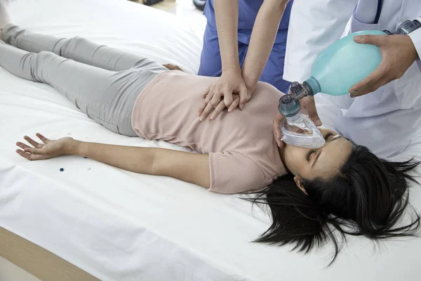 Hands of doctors giving cardiac massage and resuscitation to a female patient in the bedroom, Concept of Emergency Medical Team