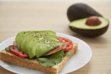 Sağlıklı sandviç avokado ve düzenlenen çavdar ekmeği ve ahşap zemin, sağlıklı gıda iş kavramlar üzerine karabiber serpin ile