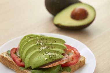 Sağlıklı sandviç avokado ve düzenlenen çavdar ekmeği ve ahşap zemin, sağlıklı gıda iş kavramlar üzerine karabiber serpin ile