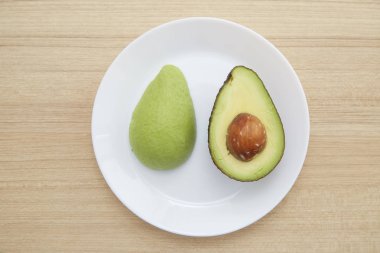 Sağlıklı Vejetaryen, kahverengi ahşap masa üzerinde beyaz plaka üzerinde avokado.