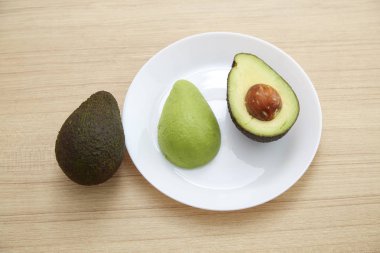 Sağlıklı Vejetaryen, kahverengi ahşap masa üzerinde beyaz plaka üzerinde avokado.