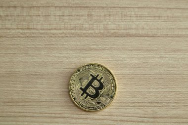 Bitcoin. Fiziksel bit sikke. Dijital para. Cryptocurrency. Ahşap masa arka plan yansıması, iş büyüme ile bitcoin sembolü ile altın sikke