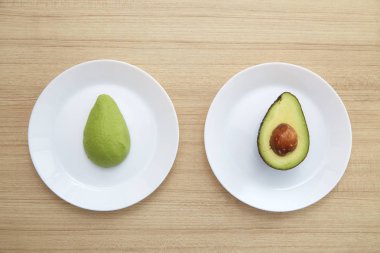 Sağlıklı Vejetaryen, kahverengi ahşap masa üzerinde beyaz plaka üzerinde avokado.