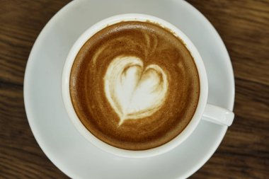 Kalp Desenli güzel latte sanat rustik ahşap zemin üzerine beyaz bir fincan kahve