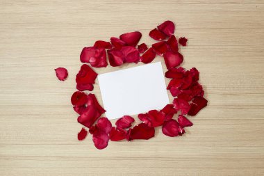 Kırmızı gül yaprakları ve beyaz boş kağıt hediye kartı ahşap arka plan üzerinde. Kavram Doğum günü Sevgililer ya da anneler günü geçmiş
