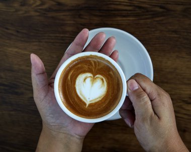 Ahşap üzerine kahve Kupası ve kadın çivi üzerinde kahve Kupası kalp holding eller, Sevgililer günü aşk kavramı.