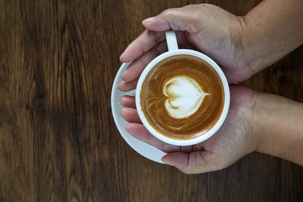 Hands holding coffee cup heart on coffee cup and woman nails on wood, valentine love concept.