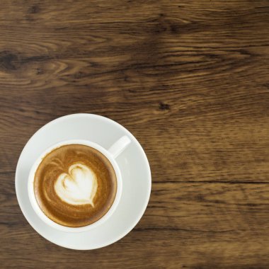 Kahve kalp desenli beyaz Kupası ve ahşap arka plan, üstten görünüm, iş online iş için fikirler akıllı telefon