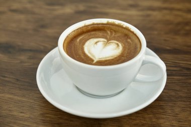 Kalp Desenli güzel latte sanat rustik ahşap zemin üzerine beyaz bir fincan kahve