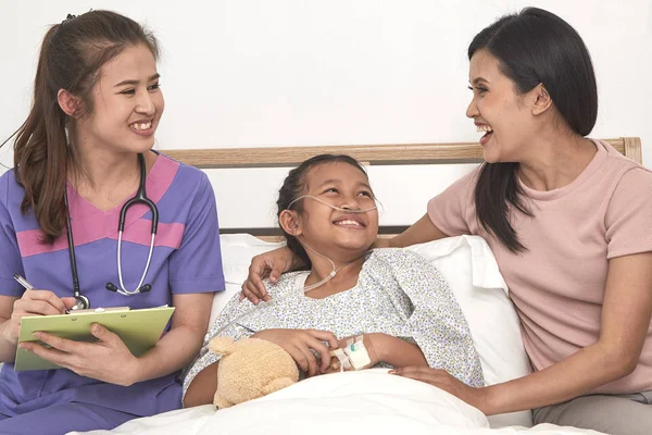 Female doctor and Young asian little patient with and mother smiling while doctor come to visit