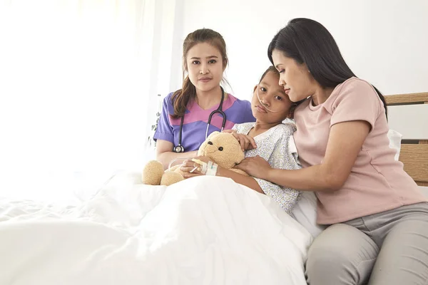 Female doctor and Young asian little patient with and mother smiling while doctor come to visit