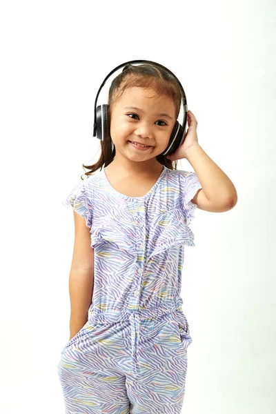 音楽を聴き コピースペースエリアを見てヘッドフォンでアジアの小さな女の子 — ストック写真
