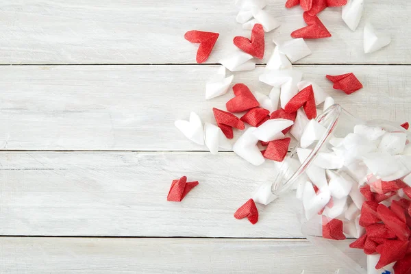 Valentine\'s Day symbolizing love Red and white origami hearts in Glass bottle white wooden table background, Empty space for simple design