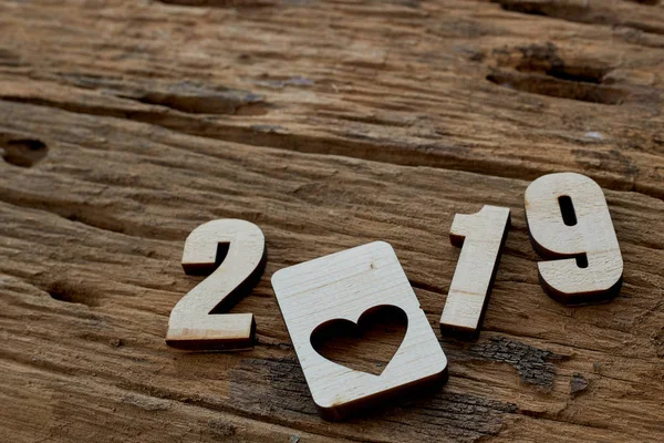 2019 wooden smooth clean hearts lying on brown wooden textured background. Empty copy space for inscription or other objects