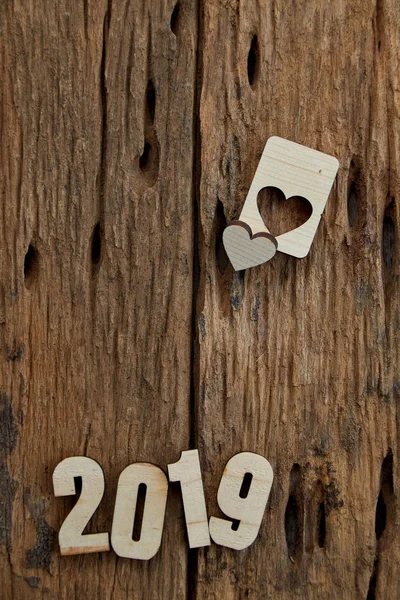 2019 wooden smooth clean hearts lying on brown wooden textured background. Empty copy space for inscription or other objects