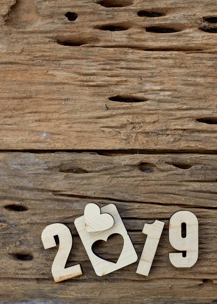 2019 wooden smooth clean hearts lying on brown wooden textured background. Empty copy space for inscription or other objects