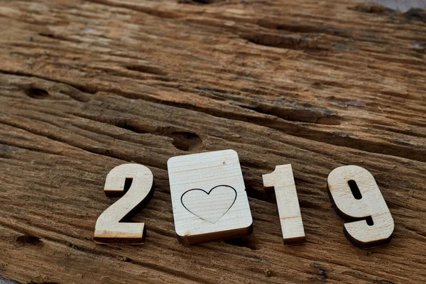 2019 wooden smooth clean hearts lying on brown wooden textured background. Empty copy space for inscription or other objects