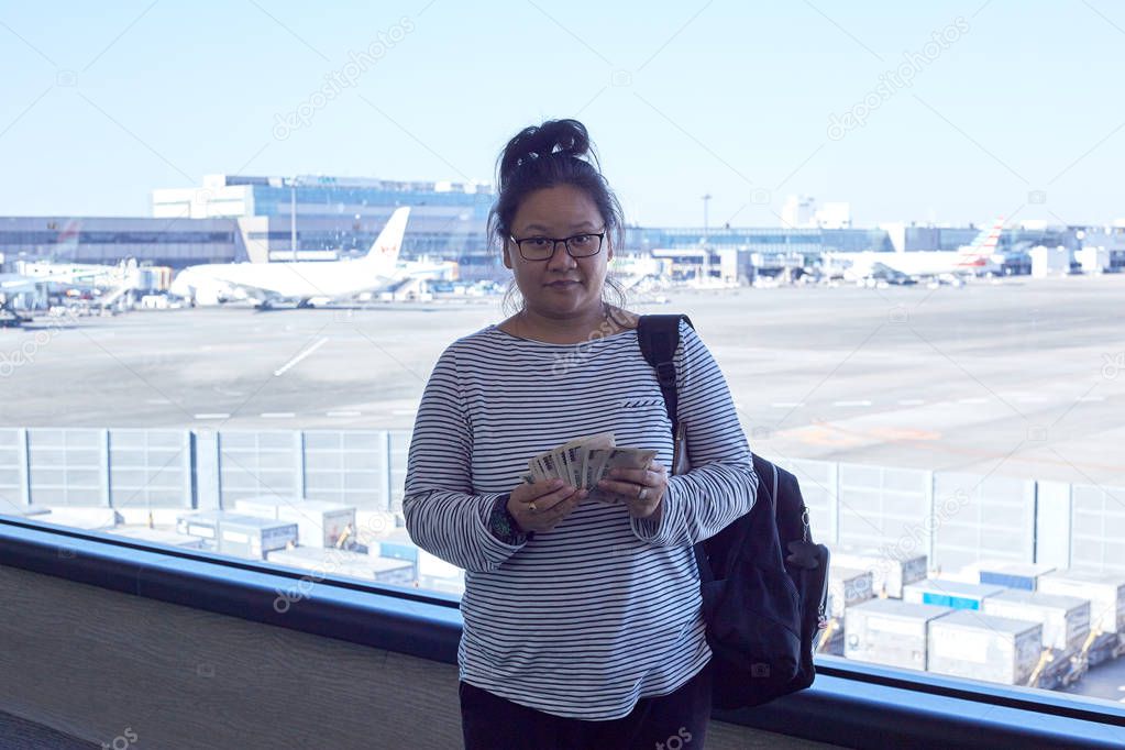 Asian Female tourists backpack standing holding money yen in the airport