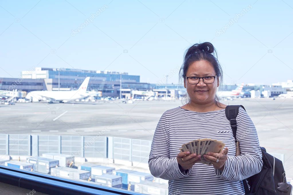 Asian Female tourists backpack standing holding money yen in the airport