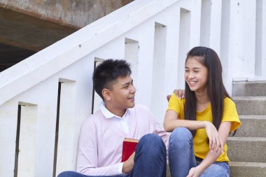 öğrenciler kitap kullanarak merdivenlerde oturan arkadaşlar