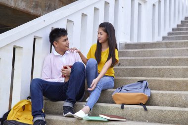 öğrenciler kitap kullanarak merdivenlerde oturan arkadaşlar