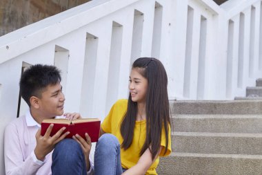 öğrenciler kitap kullanarak merdivenlerde oturan arkadaşlar