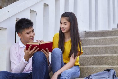 öğrenciler kitap kullanarak merdivenlerde oturan arkadaşlar