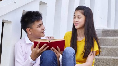 öğrenciler kitap kullanarak merdivenlerde oturan arkadaşlar