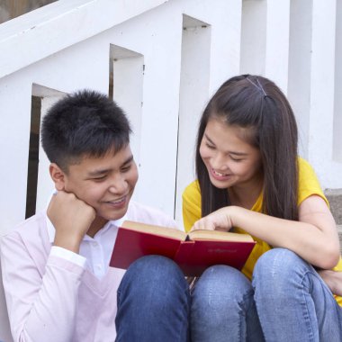 öğrenciler kitap kullanarak merdivenlerde oturan arkadaşlar