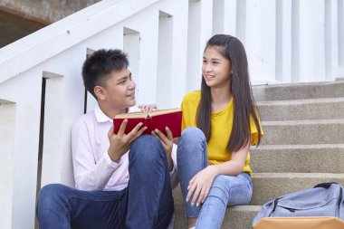 öğrenciler kitap kullanarak merdivenlerde oturan arkadaşlar