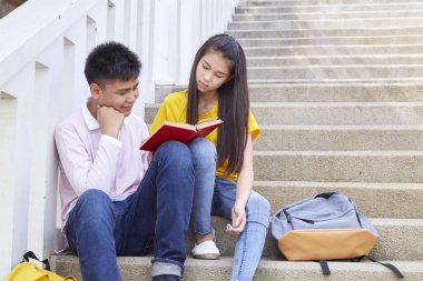 öğrenciler kitap kullanarak merdivenlerde oturan arkadaşlar