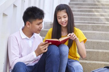 öğrenciler kitap kullanarak merdivenlerde oturan arkadaşlar