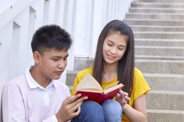 öğrenciler kitap kullanarak merdivenlerde oturan arkadaşlar