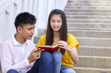 öğrenciler kitap kullanarak merdivenlerde oturan arkadaşlar