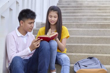 öğrenciler kitap kullanarak merdivenlerde oturan arkadaşlar