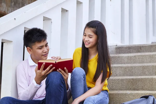 Studenti amici seduti sulle scale utilizzando libro — Foto Stock